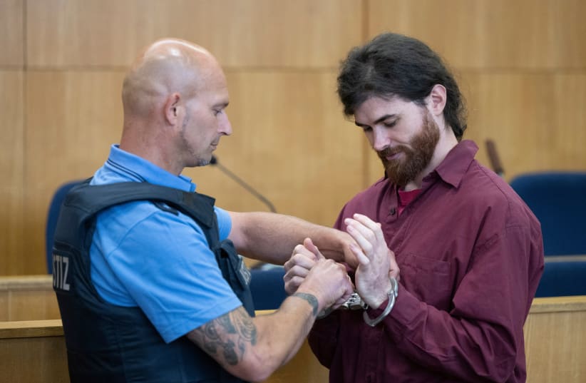  Franco A., a 32-year-old former soldier of Germany's army Bundeswehr, accused of posing under a false identity as an asylum seeker in 2017 and planning an attack on high-ranking officials, gets his handcuffs removed as he arrives for his verdict at a regional court in Frankfurt, Germany. (photo credit: BORIS ROESSLER/POOL VIA REUTERS)