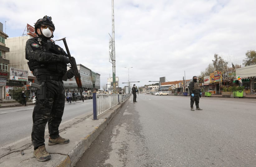 Security men stand in an empty street during a curfew imposed by Iraqi Kurdish authorities, following the outbreak of coronavirus, in Sulaimaniya, in Iraqi Kurdistan, lraq, March 14, 2020. (photo credit: REUTERS/AKO RASHEED)