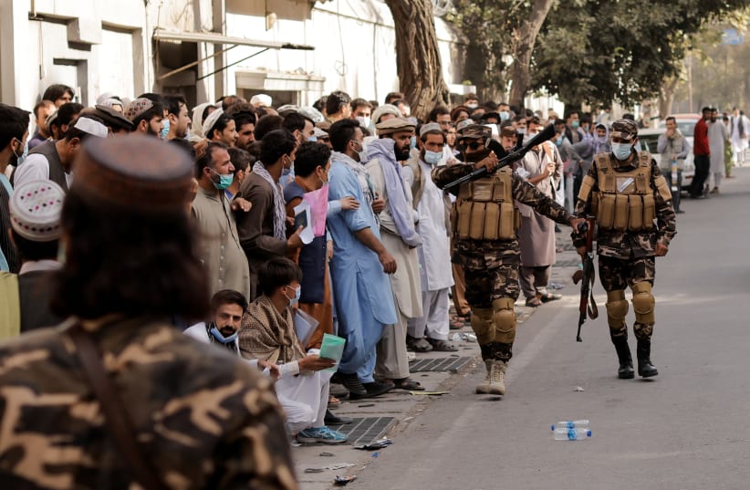  Members of Taliban forces control people waiting to get visas, at the Iran embassy in Kabul, Afghanistan October 4, 2021 (photo credit: REUTERS/JORGE SILVA)