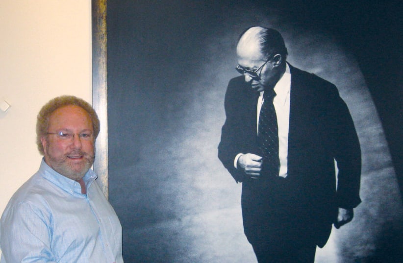  The author standing next to a photo of Begin at the Menachem Begin Heritage Center in Jerusalem.   (photo credit: STEVE NORTH)