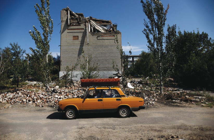  A 62-YEAR-OLD Ukrainian man drives off in a car after leaving his destroyed house, in Toretsk, Donetsk region, on Monday. Since February, Ukraine has been fighting an enemy whose declared aim is to wipe it off the map (photo credit: AMMAR AWAD/REUTERS)