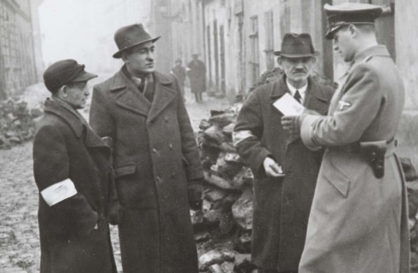 A German policeman checks the identification papers of Jewish people in the Krakow, Poland, 1941. (photo credit: NATIONAL ARCHIVES IN KRAKOW/VIA JTA)