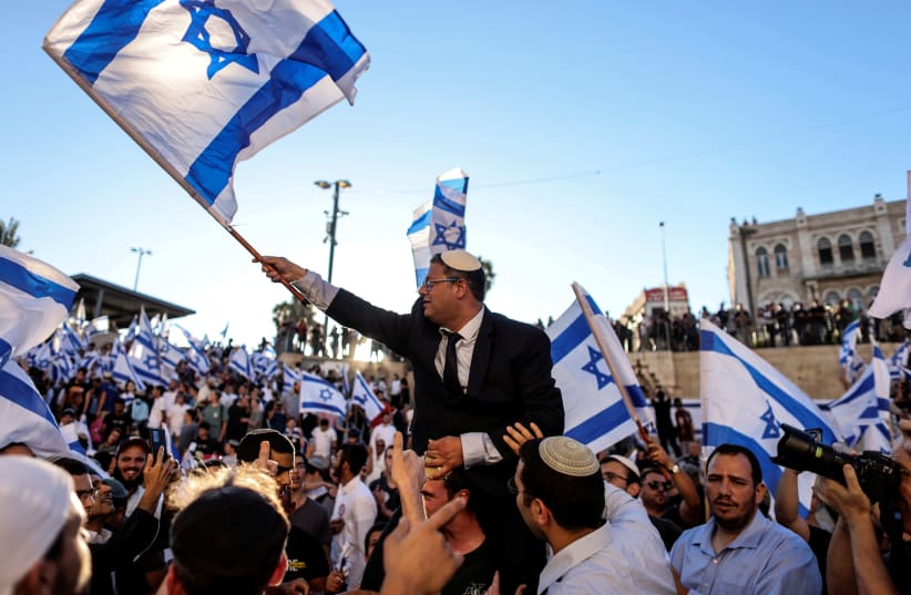 Israeli lawmaker Itamar Ben Gvir carries an Israeli flag as he dances together with others by Damascus gate just outside Jerusalem's Old City June 15, 2021 (photo credit: REUTERS/RONEN ZEVULUN)