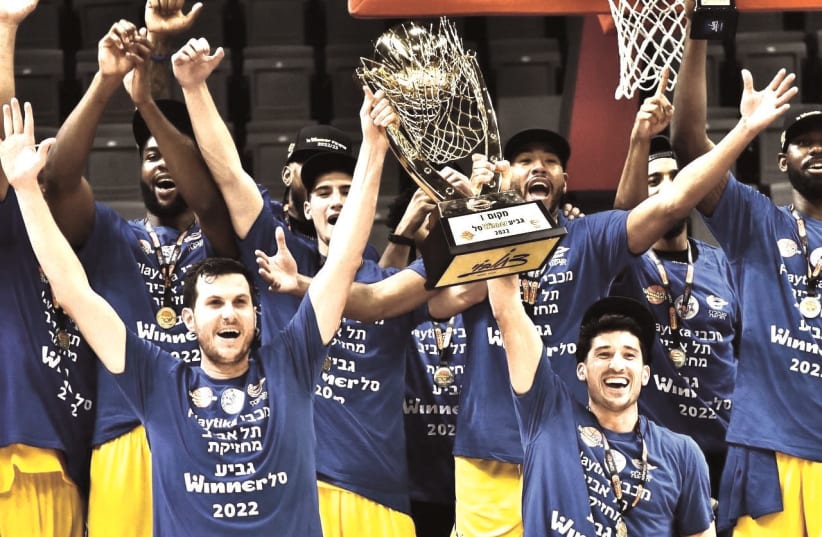   MACCABI TEL AVIV players celebrate on the court with the trophy following their 88-84 overtime victory over Hapoel Tel Aviv in the Winner Cup final (photo credit: YEHUDA HALICKMAN)