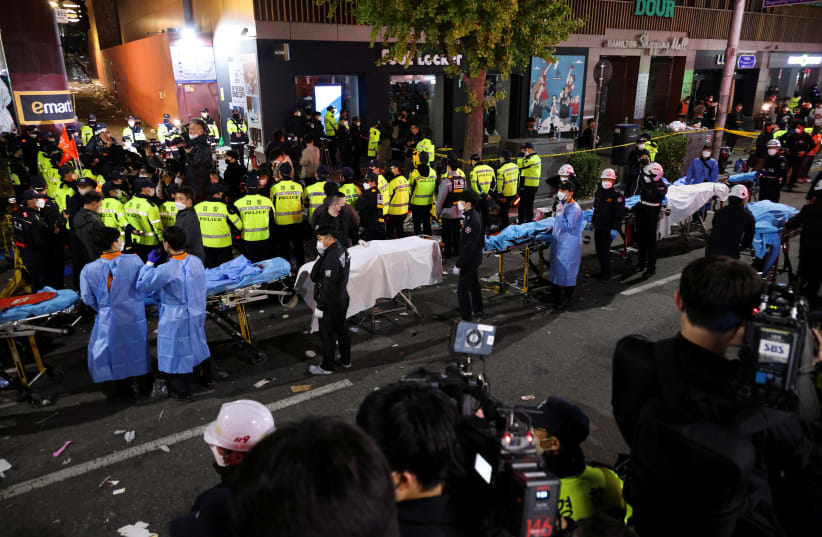  Rescue team members wait with stretchers to remove bodies from the scene where dozens of people were injured in a stampede during a Halloween festival in Seoul, South Korea (photo credit: REUTERS)