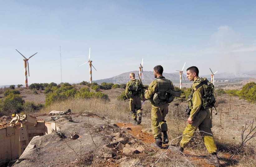  IDF soldiers walk in front of wind turbines close to the Israeli-Syrian border in the Golan Heights. (photo credit: NIR ELIAS/REUTERS)
