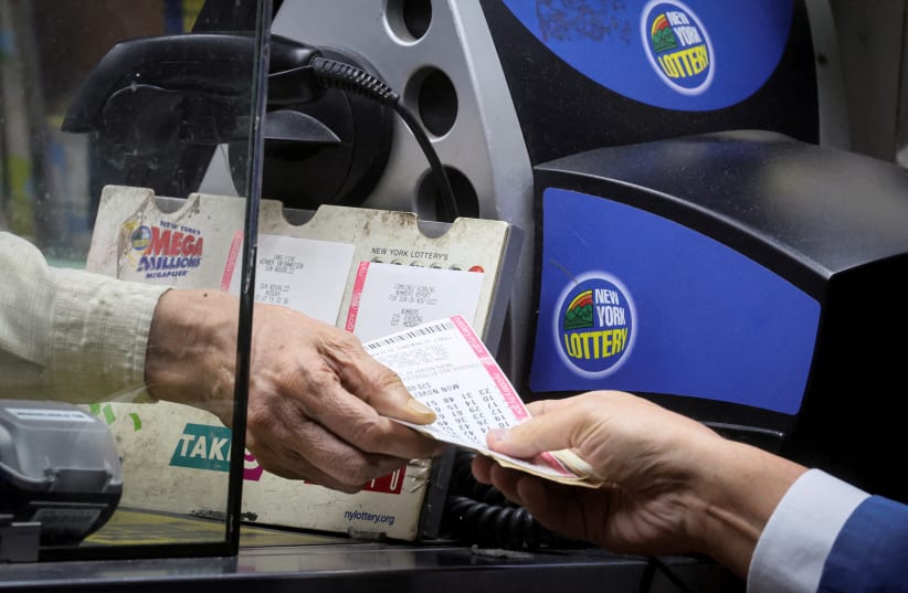  A customer purchases a ticket for the Powerball jackpot at a newsstand in New York City, US, November 7, 2022 (photo credit: REUTERS/BRENDAN MCDERMID)