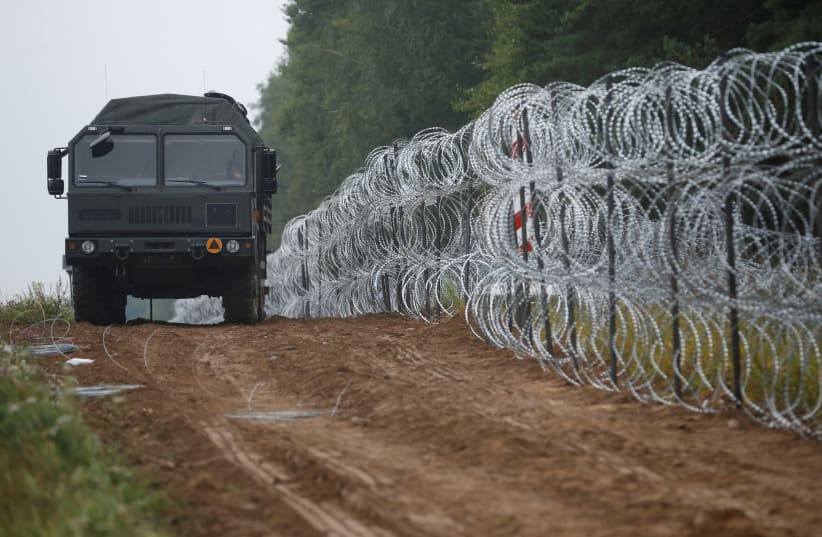  A view of a vehicle next to a fence built by Polish soldiers on the border between Poland and Belarus near the village of Nomiki, Poland August 26, 2021. (photo credit: REUTERS/KACPER PEMPEL)