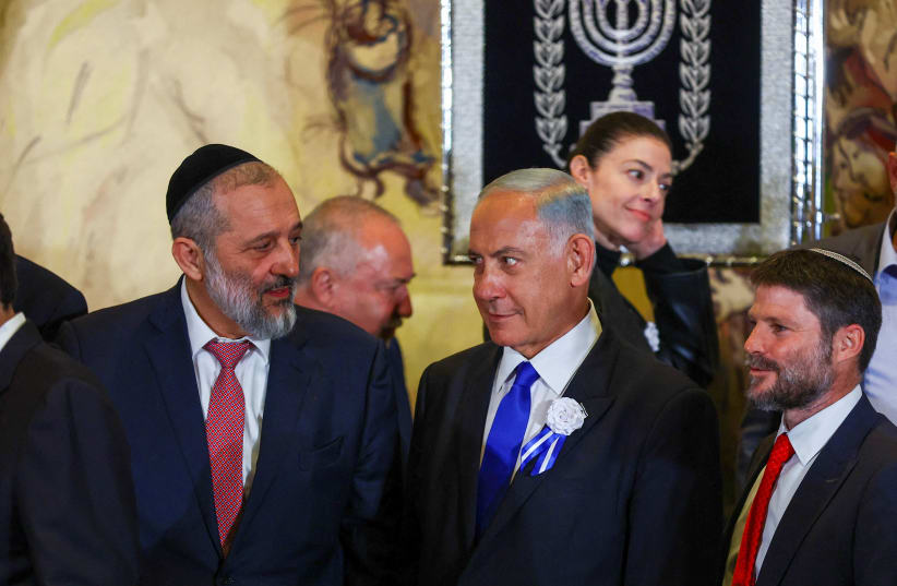  Benjamin Netanyahu looks at Shas leader MK Aryeh Deri as they stand with other members of the new Israeli parliament after their swearing-in ceremony in Jerusalem November 15, 2022.  (photo credit: RONEN ZVULUN/REUTERS)