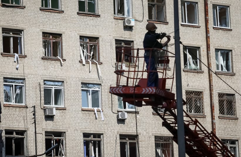  A communal worker restores electricity near a building destroyed in an air strike, amid Russia's invasion of Ukraine, in Kyiv, Ukraine April 29, 2022 (photo credit: GLEB GARANICH/REUTERS)