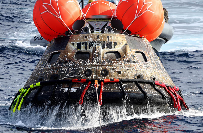 NASA's Orion Capsule is drawn to the well deck of the USS Portland after it splashed down following a successful uncrewed Artemis I Moon Mission on December 11, 2022 in the Pacific Ocean off the coast of Baja California, Mexico. (photo credit: MARIO TAMA/POOL VIA REUTERS)