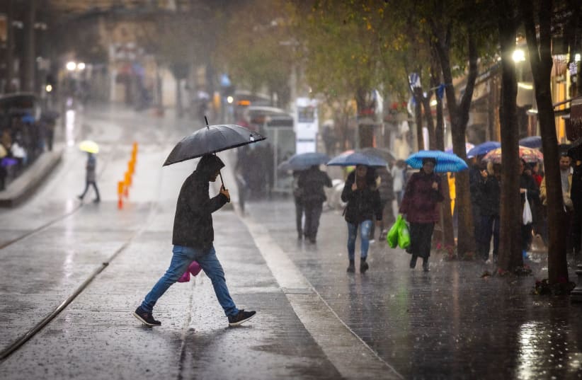  People take cover from the rain as they walk  in the city center of Jerusalem on December 26, 2022.  (photo credit: OLIVIER FITOUSSI/FLASH90)