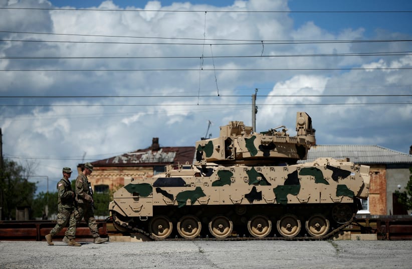 US servicemen walk past a Bradley infantry fighting vehicle as they arrive for the joint U.S.-Georgian exercise Noble Partner 2016 in Vaziani, Georgia, May 5, 2016 (photo credit: REUTERS/DAVID MDZINARISHVILI)