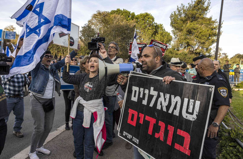  A right-wing activist, carrying a sign that reads "leftists traitors," confronts left-wing activists at an anti-government demonstration near the Knesset in Jerusalem, Dec. 12, 2022.  (photo credit: Menahem Kahana/AFP via Getty Images)