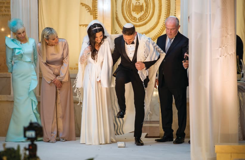  DANEL JAFFE breaks a glass at his wedding as his bride, Roni, his mother, Tamar (in blue), the bride’s mother, Yael Levin, and the groom’s father, Zalli Jaffe, look on. (photo credit: Asaf Kriger)