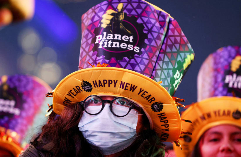  A person wearing a face mask is seen amongst revelers in Times Square during the first New Year's Eve event without restrictions since the coronavirus disease (COVID-19) pandemic in the Manhattan borough of New York City, New York, US, December 31, 2022. (photo credit: REUTERS/ANDREW KELLY)