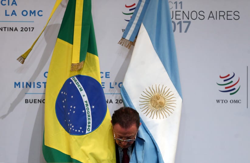  A man places the national flags of Brazil and Argentina before the opening ceremony of the World Trade Organization's ministerial conference in Buenos Aires, Argentina December 10, 2017 (photo credit: MARCOS BRINDICCI)