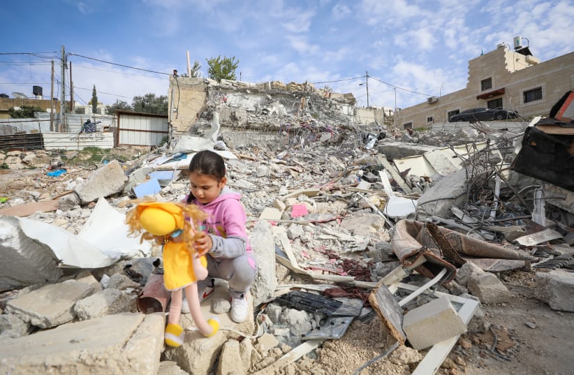  A girl clutches a doll as she sits among the rubble of a building  demolished by Israeli security forces in the east Jerusalem Neighborhood of Jabel Mukaber, January 29, 2023. (photo credit: JAMAL AWAD/FLASH90)