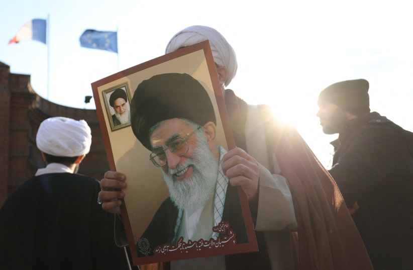  An Iranian cleric holds a picture of Ayatollah Ali Khamenei, during a protest to condemn the French magazine Charlie Hebdo for republishing cartoons insulting Iran's Supreme Leader Ayatollah Ali Khamenei, in front of the French Embassy in Tehran, Iran, January 8, 2023 (photo credit: MAJID ASGARIPOUR/WANA (WEST ASIA NEWS AGENCY) VIA REUTERS)
