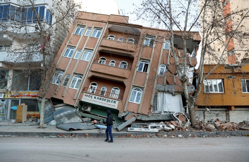  A man walks past a partially collapsed building, in the aftermath of a deadly earthquake, in Pazarcik, Turkey February 9, 2023 (photo credit: REUTERS/SUHAIB SALEM)