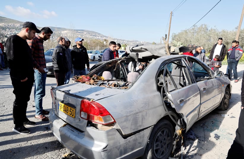  People look at a damaged car where three Palestinian militants were killed during an Israeli operation, near Jenin, in the West Bank, March 9, 2023 (photo credit: REUTERS/RANEEN SAWAFTA)