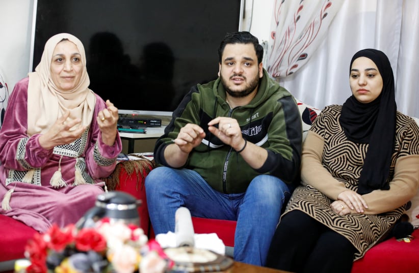 Palestinian Omar Khalifa sits with his family, after on Monday Israeli settlers attacked a car while he was in it with his family in Huwara, in his home in Asira al-Qibliya in the West Bank, March 7, 2023. (photo credit: REUTERS/RANEEN SAWAFTA)