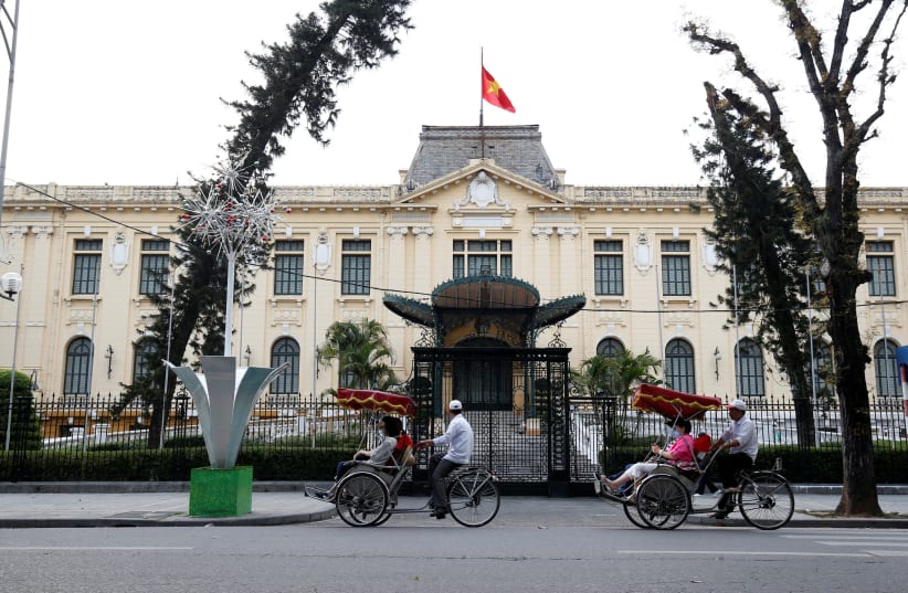  Men transport people on three-wheel cyclo past the Government Guesthouse in Hanoi, Vietnam February 20, 2019. (photo credit: KHAM / REUTERS)