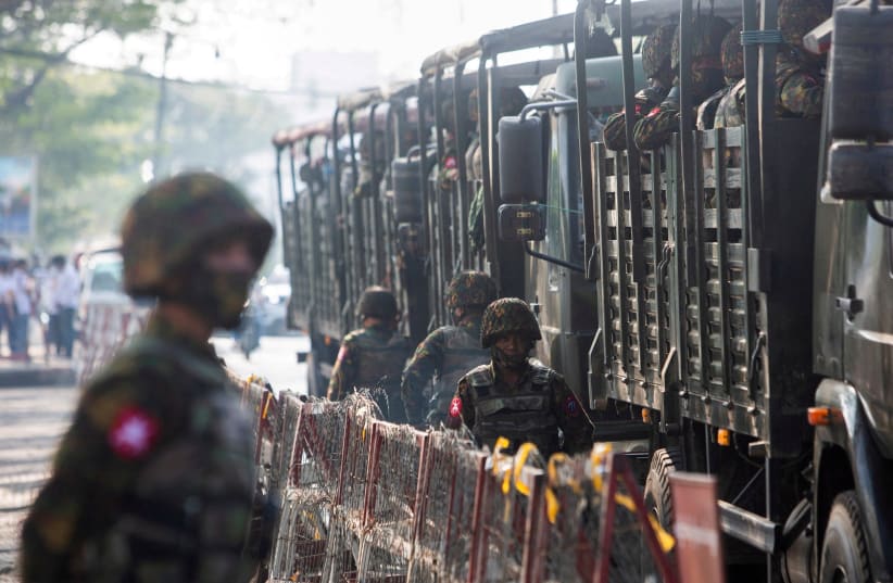  Soldiers stand next to military vehicles as people gather to protest against the military coup, in Yangon, Myanmar, February 15, 2021. (photo credit: STRINGER/ REUTERS)