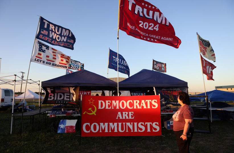  A supporter of former U.S. president Donald Trump walks pass merchant booths ahead of the Trump's first campaign rally after announcing his candidacy for president in the 2024 election at an event, in Waco, Texas, US, March 24, 2023. (photo credit: REUTERS/JIM URQUHART)