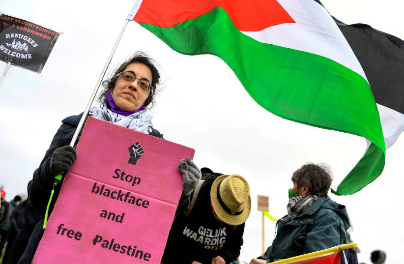  A woman holds a placard and a flag of Palestine during a demonstration against racism in Amsterdam, Netherlands, March 21, 2021 (photo credit: REUTERS/PIROSCHKA VAN DE WOUW)