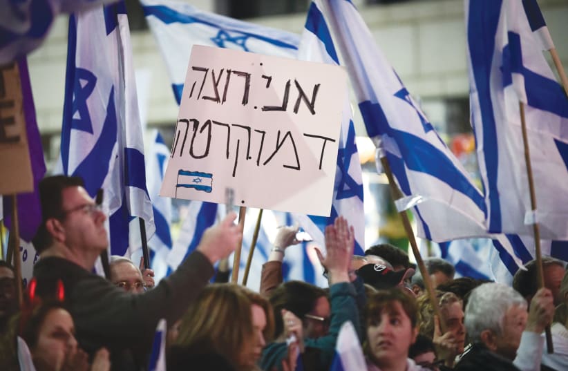  A PROTESTER holds a sign that reads: ‘I want democracy,’ at a demonstration in Herzliya, earlier this year.  (photo credit: AVSHALOM SASSONI/FLASH90)