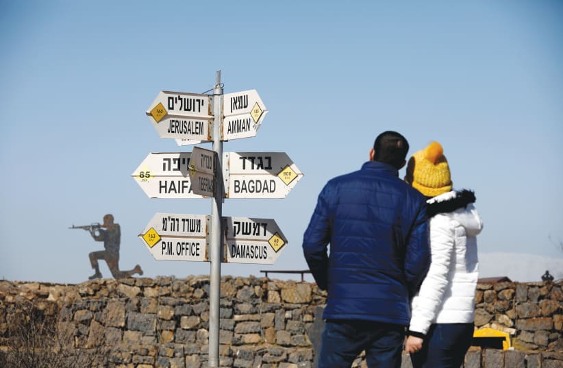  A COUPLE look at signs pointing the direction and distance to different cities on Mount Bental, an observation post on the Golan Heights that overlooks the Syrian side of the Quneitra crossing.  (photo credit: AMIR COHEN/REUTERS)