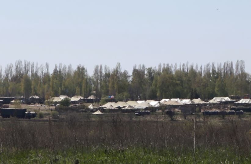  Russian military vehicles and army tents are seen in a field outside the village of Severny in Belgorod region near the Russian-Ukrainian border, April 25, 2014 (photo credit: REUTERS/SERGEI KHAKHALEV)