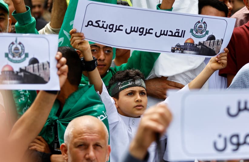   boy holds a placard as Palestinian Hamas supporters attend a rally against visits by Israeli right wing groups to Al-Aqsa mosque, in Khan Younis in the southern Gaza Strip May 26, 2023 (photo credit: REUTERS/IBRAHEEM ABU MUSTAFA)