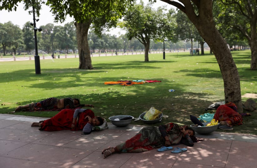  Women labourers rest under a tree on a hot summer day near India Gate, in New Delhi, India May 15, 2023 (photo credit: REUTERS)