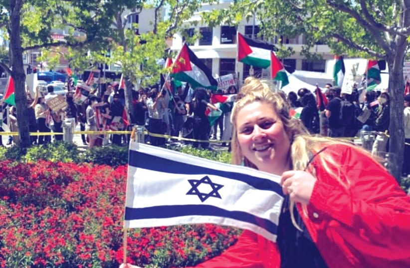  THE WRITER displays an Israeli flag, as a pro-Palestinian demonstration takes place, in Los Angeles, last year (photo credit: Naya Lekht)