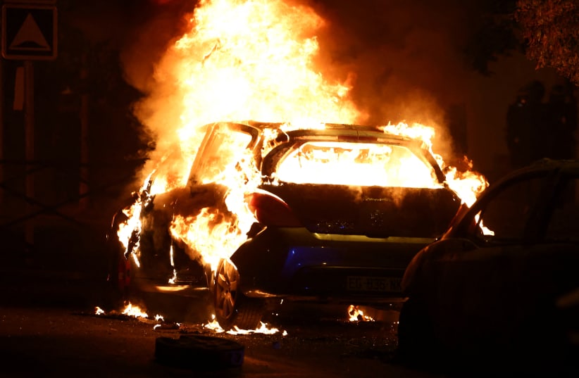  A vehicle burns during clashes between protesters and police, after the death of Nahel, a 17-year-old teenager killed by a French police officer during a traffic stop, in Nanterre, Paris suburb, France, June 28, 2023 (photo credit: REUTERS/Stephanie Lecocq)