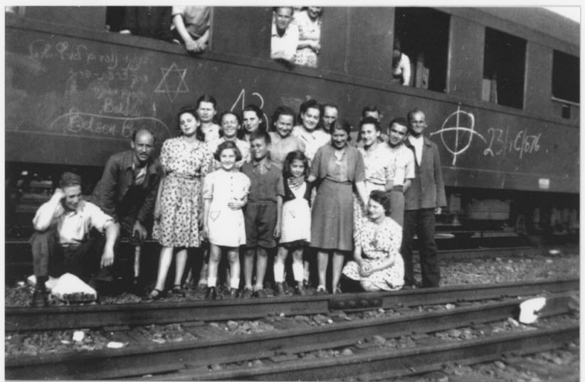  Prisoners from an evacuation train from Bergen-Belsen pose next to a railroad car in Magdeburg.  This photo was probably taken a few days after liberation since written on the side of the car is "Bergen-Belsen" and "We are going to Israel by way of France." (photo credit: Copyright: United States Holocaust Memorial Museum Provenance: Mark Nusbaum)