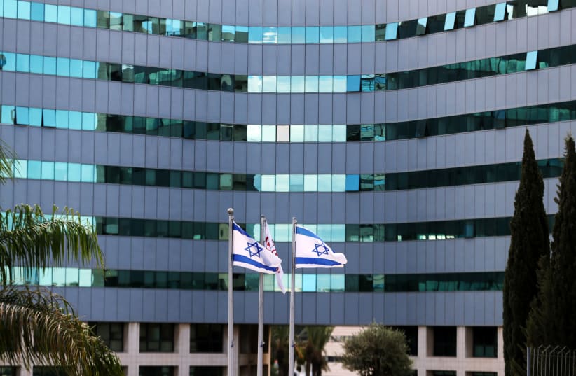  Israeli national flags flutter in front of an office tower at a business park also housing high tech companies, at Ofer Park in Petah Tikva, Israel August 27, 2020. (photo credit: REUTERS/Ronen Zvulun)