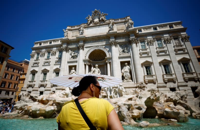 A woman shelters from the sun under an umbrella at Trevi fountain during hot weather as a heat wave hits Europe in Rome, Italy, July 19, 2022. (photo credit: GUGLIELMO MANGIAPANE / REUTERS)