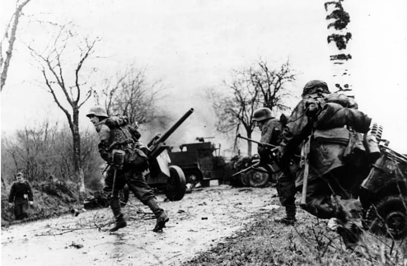  German troops advancing past American equipment during the Battle of the Bulge. (photo credit: WALLPAPER FLARE)
