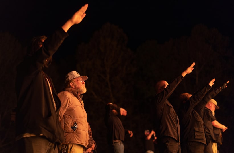  Supporters of the National Socialist Movement, a white nationalist political group, give Nazi salutes while taking part in a swastika burning at an undisclosed location in Georgia, U.S. on April 21, 2018. (photo credit: REUTERS)