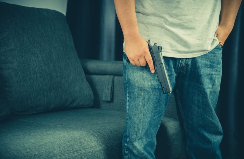  Men wearing t-shirts, jeans Standing holding a gun in the house (photo credit: INGIMAGE)