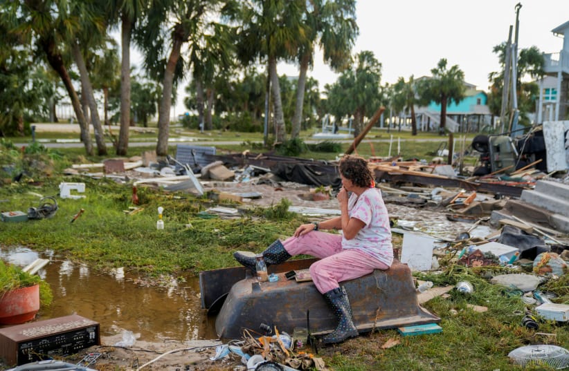 Jewell Baggett, 51, sits on a bathtub amid the wreckage of the home built by her grandfather, where she grew up and three generations of her family lived, and which Hurricane Idalia had reduced to rubble, in Horseshoe Beach, Florida, U.S., August 30, 2023. (photo credit: REUTERS/Cheney Orr)