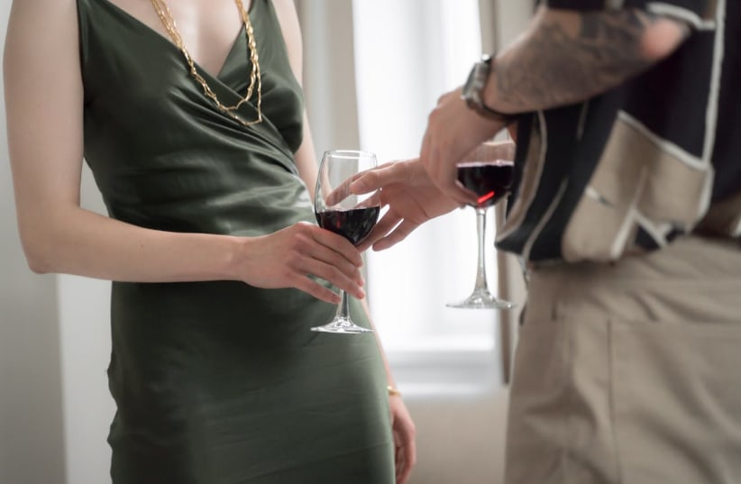  A man gives a woman a glass of wine. (photo credit: PEXELS)
