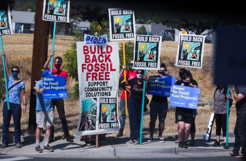 Protesters against fossil fuel hold signs along a road as U.S. President Joe Biden visits Mather, California, U.S., September 13, 2021. (photo credit: LEAH MILLIS/REUTERS)