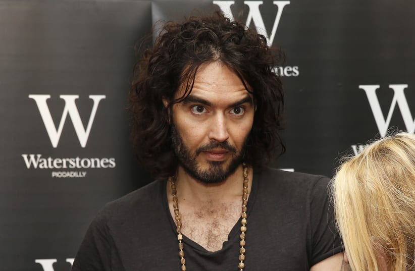 Comedian Russell Brand signs a copy of his new book entitled "Revolution" for fan Amber Smith of Hastings, in central London, December 5, 2014. (photo credit: REUTERS/SUZANNE PLUNKETT)