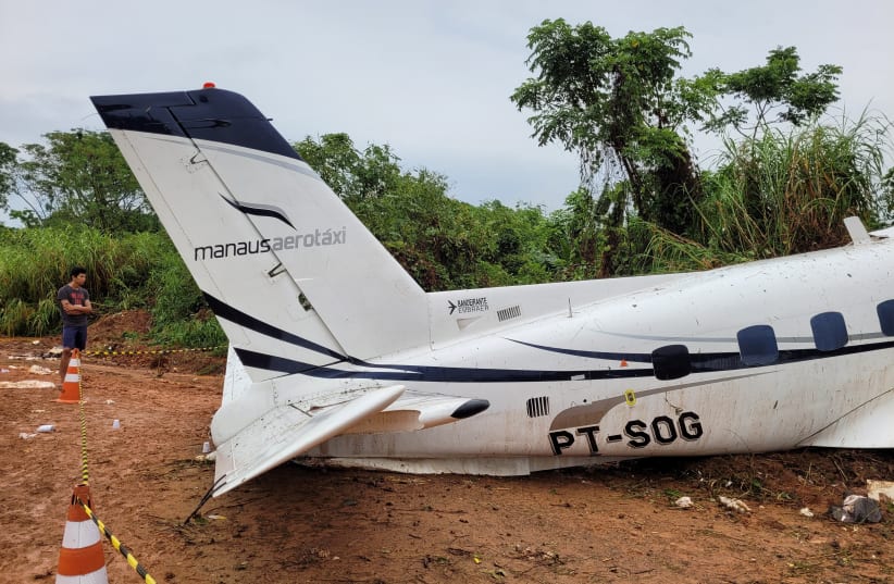 A man stands near an aircraft after it crashed, which has left 14 dead, in Barcelos, Amazonas State, Brazil September 16, 2023. (photo credit: REUTERS/Wellington Melo)