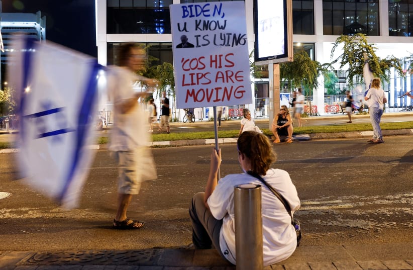  A person sits while holding a placard during a protest as the new Jewish New Year begins in a protest against Prime Minister Benjamin Netanyahu and his nationalist coalition government's judicial reform, in Tel Aviv, Israel, September 17, 2023 (photo credit: REUTERS/AMIR COHEN)