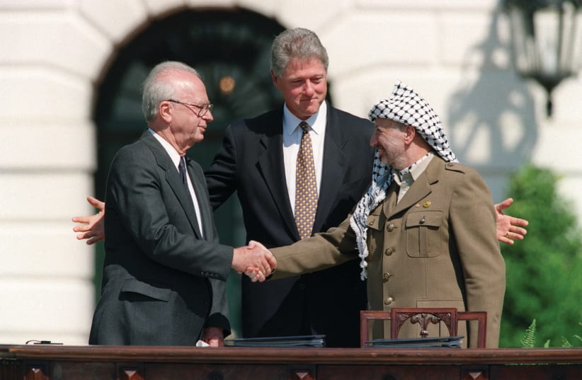  THE FAMOUS handshake: Prime minister Yitzhak Rabin seals the deal with PLO leader Yasser Arafat as US president Bill Clinton admires his handiwork, at the White House upon the signing of the Oslo Accords, Sept. 13, 1993.  (photo credit: J. David Ake/AFP via Getty Images)